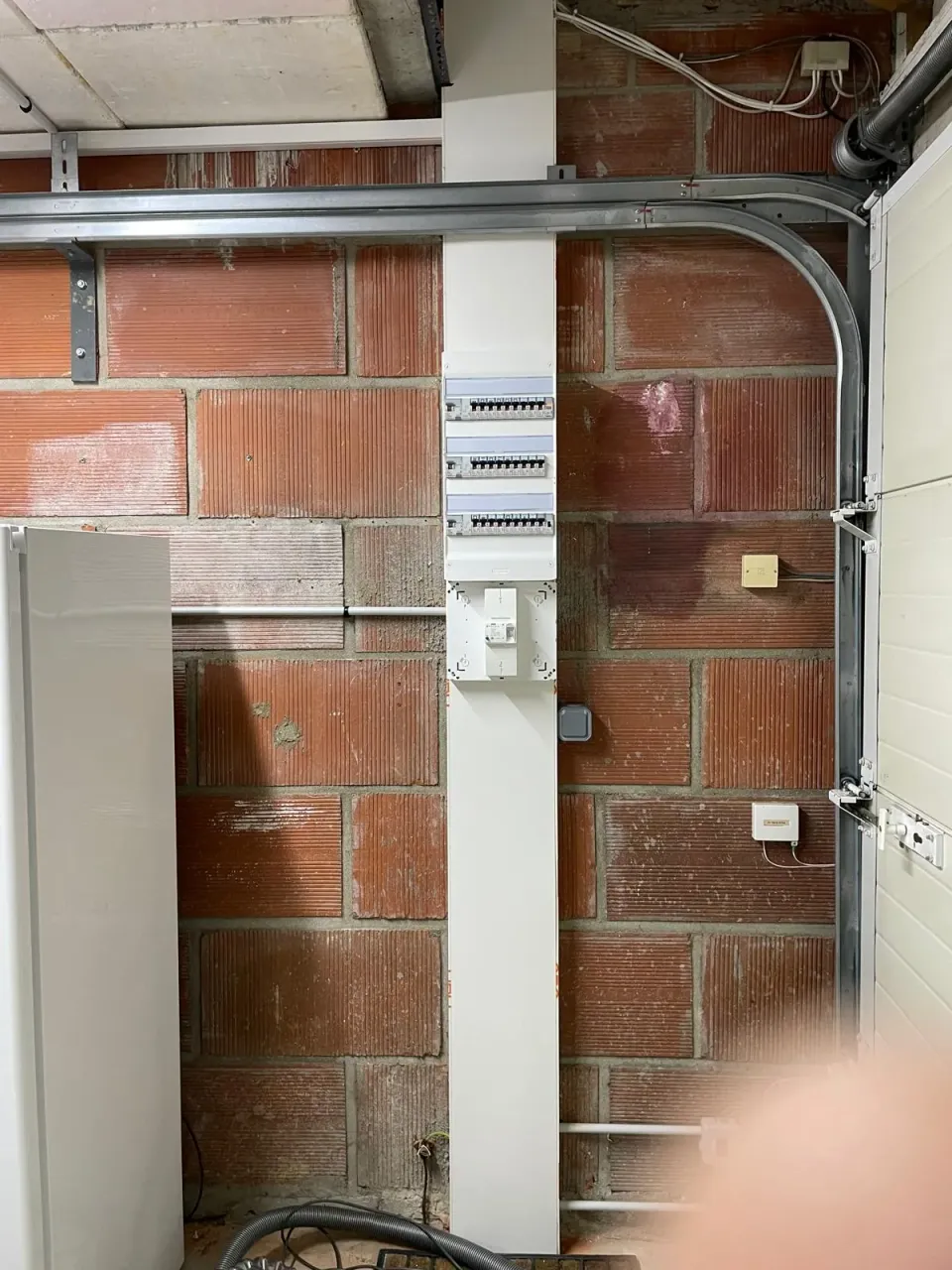 Tableau électrique neuf installé dans un garage sur mur en brique – installation électrique de maison